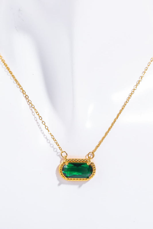Gold necklace with a green gemstone on a white background