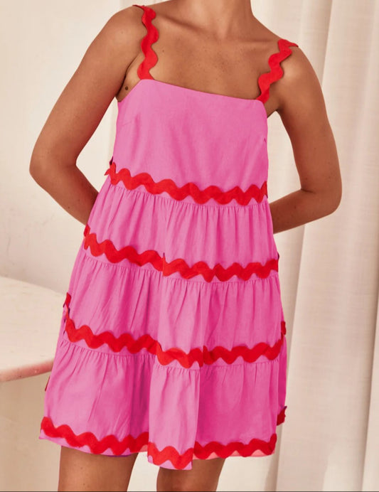 Pink dress with red ruffled details on a plain background
