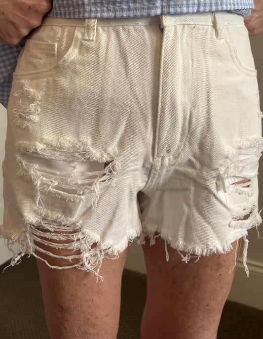 Woman wearing white distressed denim shorts