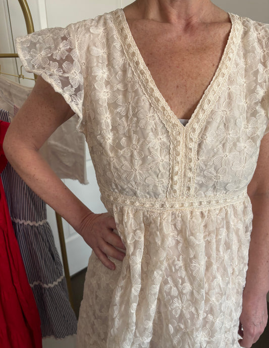 Woman wearing a beige lace dress with a blurred background