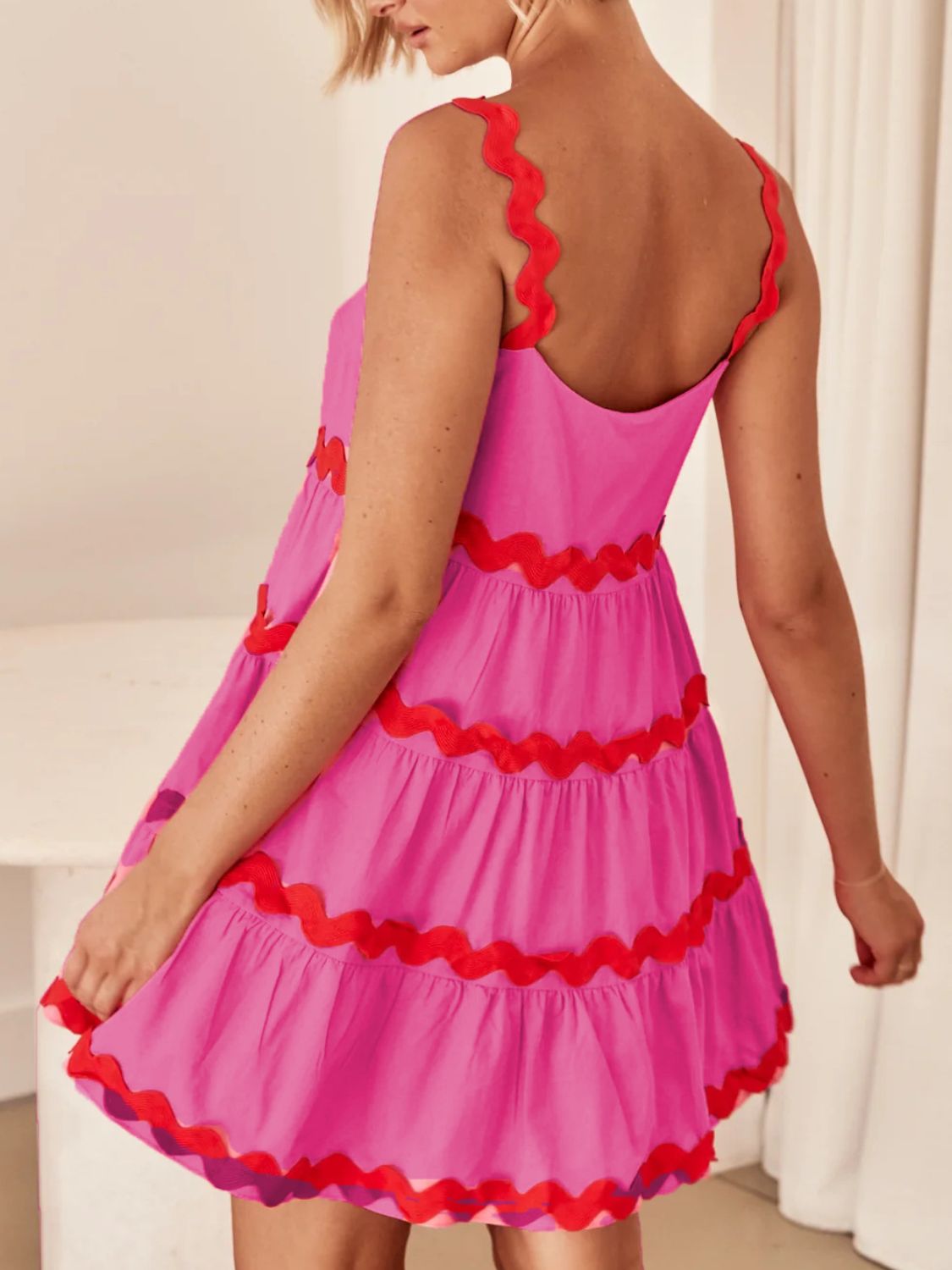 Pink dress with red trim worn by a person indoors