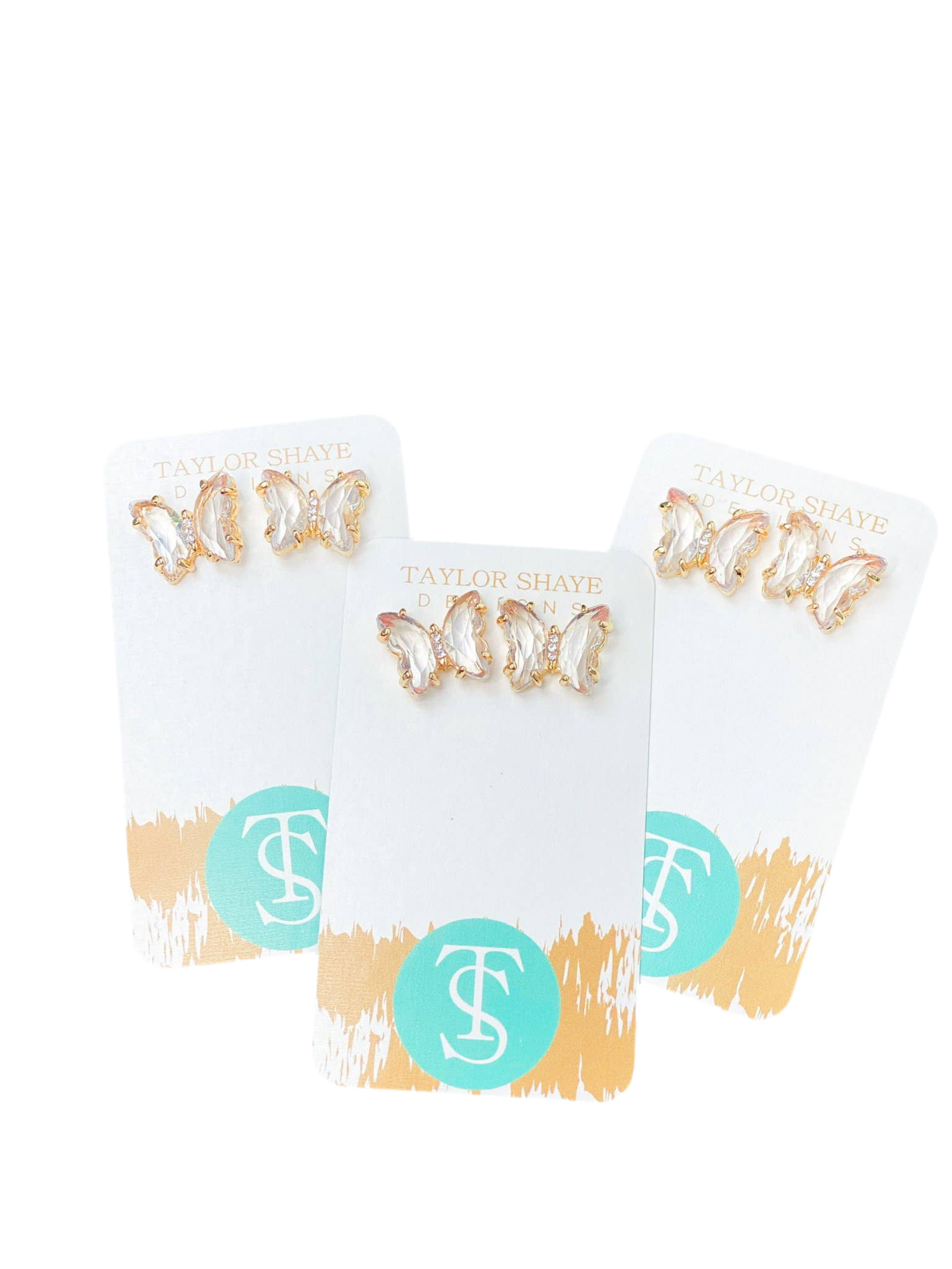 Three pairs of butterfly-shaped stud earrings on a white card with a brand logo, against a white background.