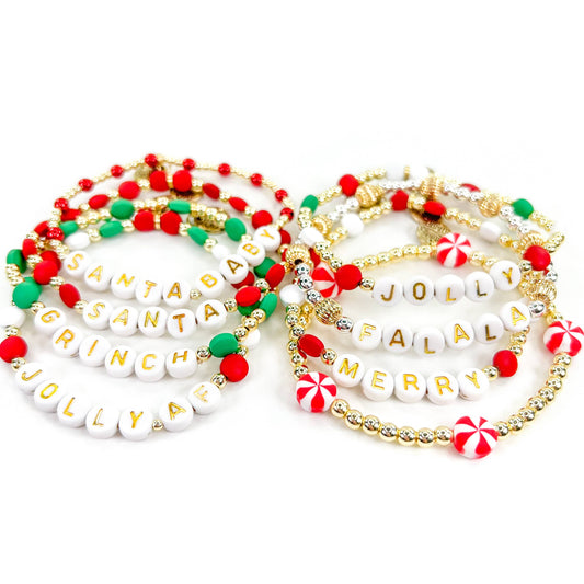 Two gold-filled bracelets with red and green beads, featuring white enamel letters spelling out 'Santa Claus' and 'Merry'.