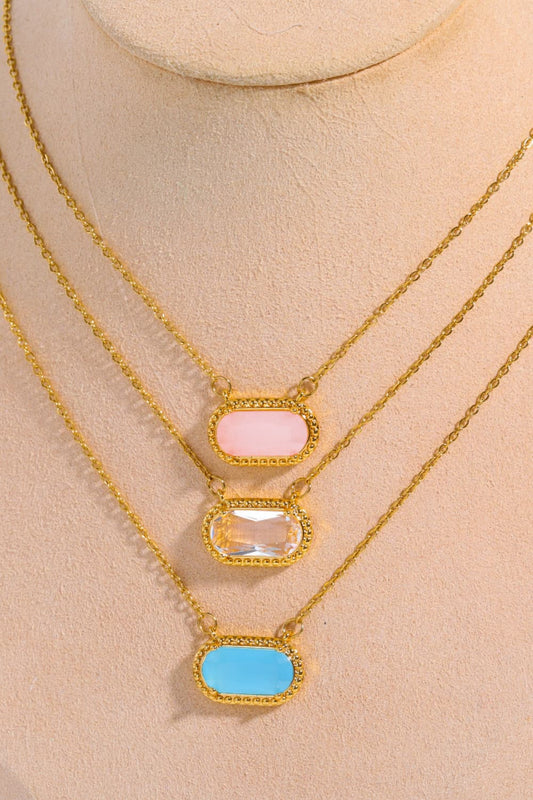 Three gold necklaces with different colored pendants on a mannequin bust.
