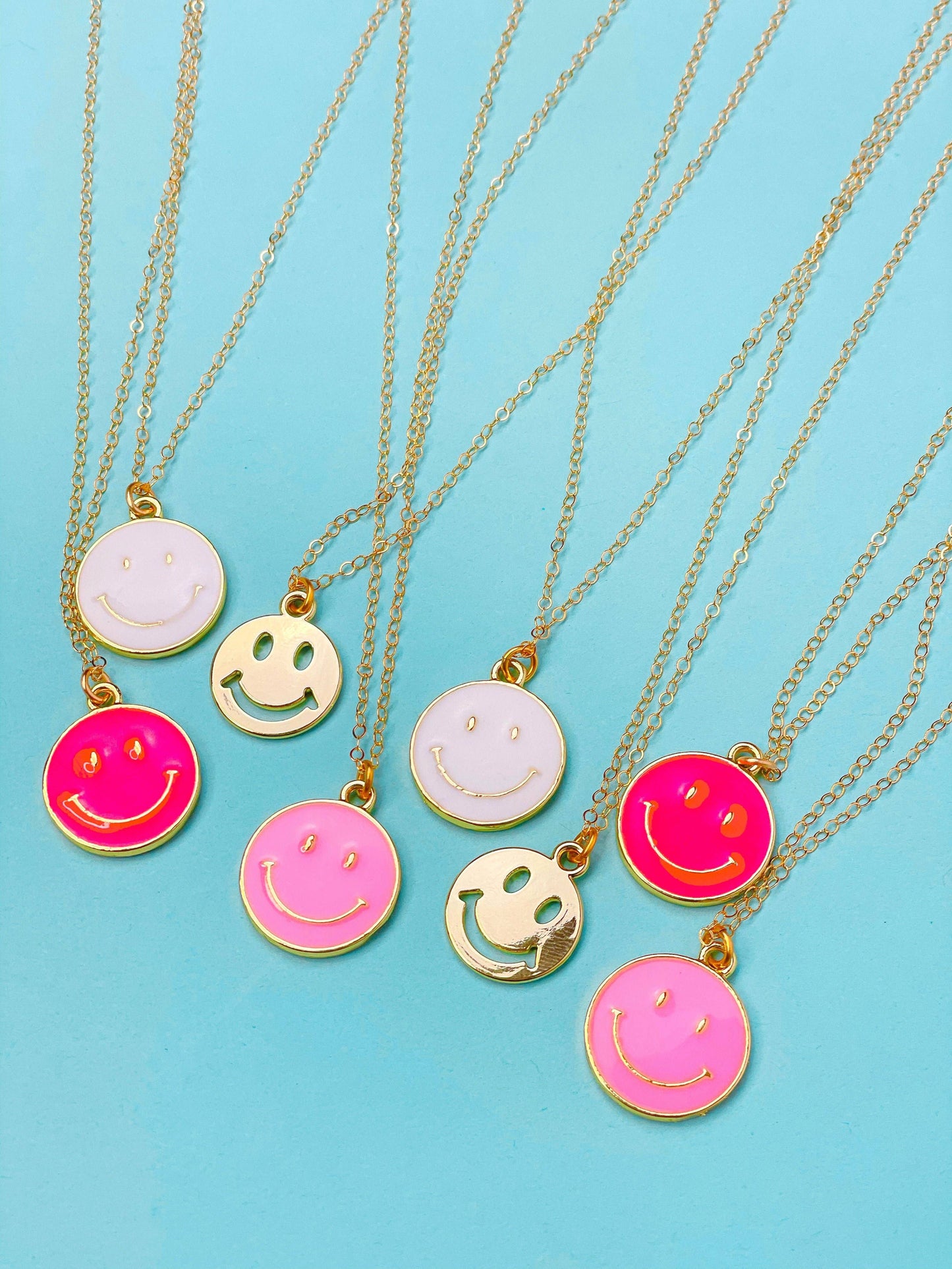 A collection of dainty chain necklaces with smiley face pendants in various colors.