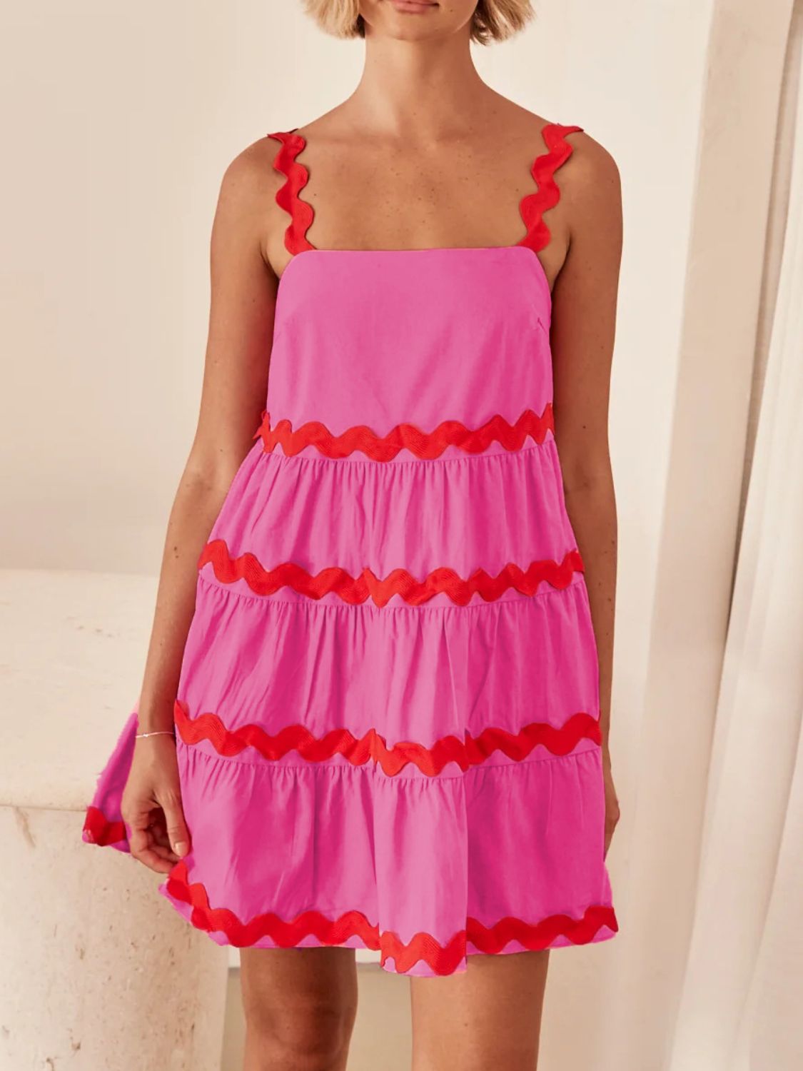 Pink dress with red ruffled trim worn by a person against a neutral background