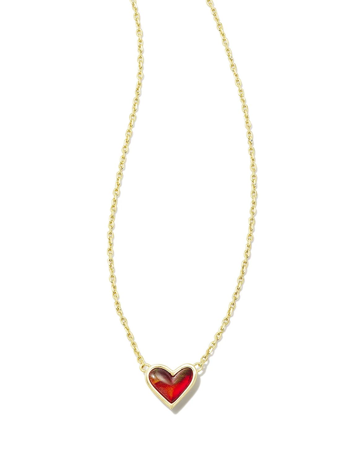 Gold necklace with a heart-shaped deep red pendant on a white background