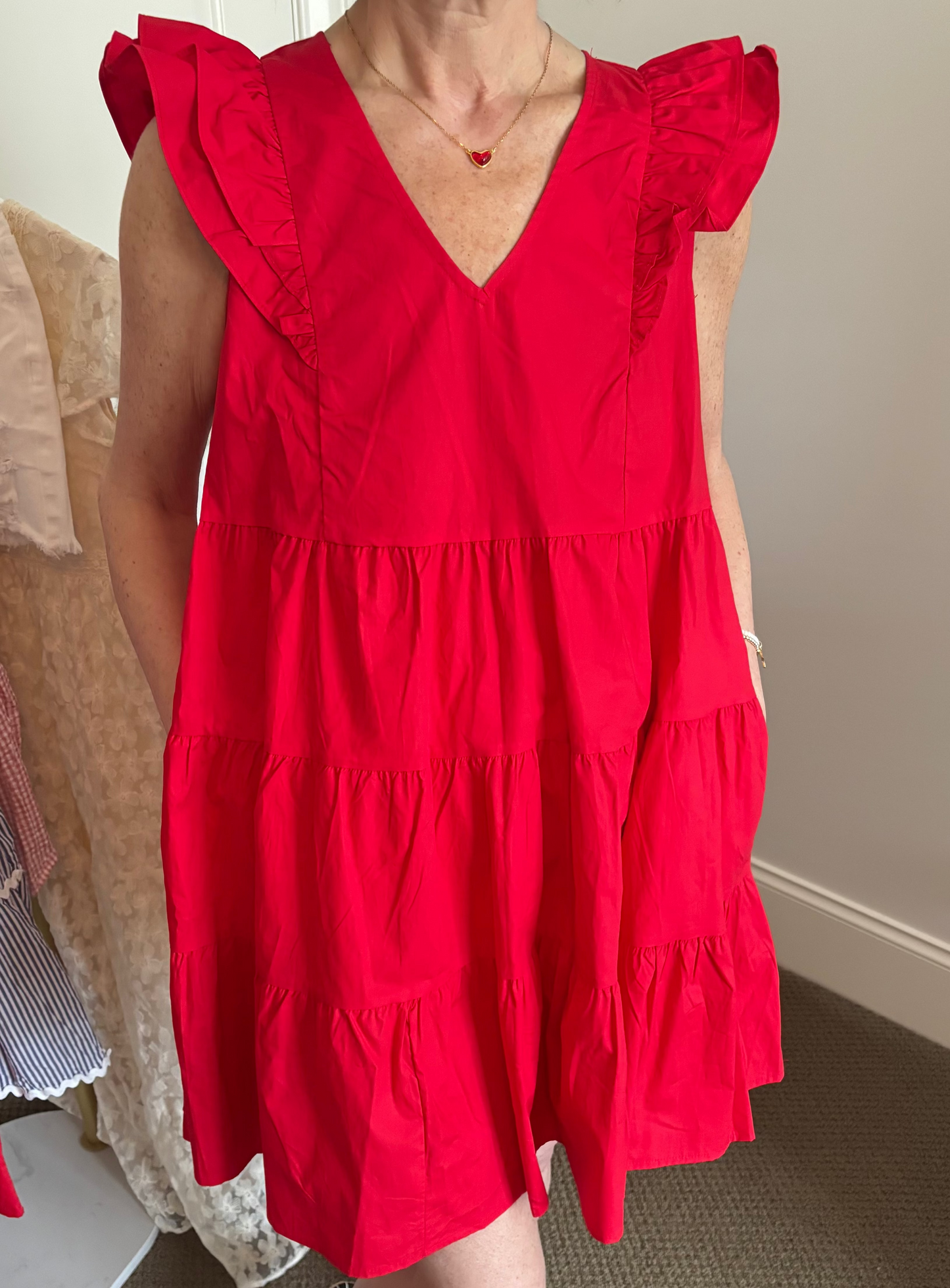 Red dress with ruffled sleeves and tiered skirt worn by a person, with a neutral background.