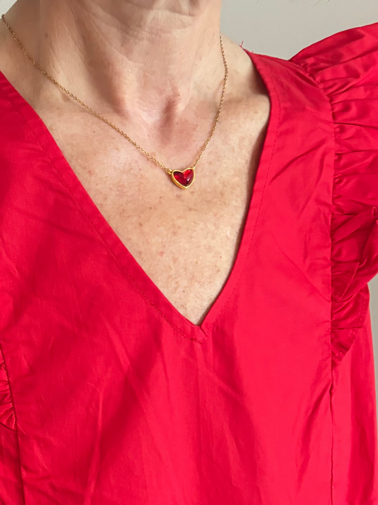 Red dress with a deep red necklace featuring a heart pendant on a neutral background
