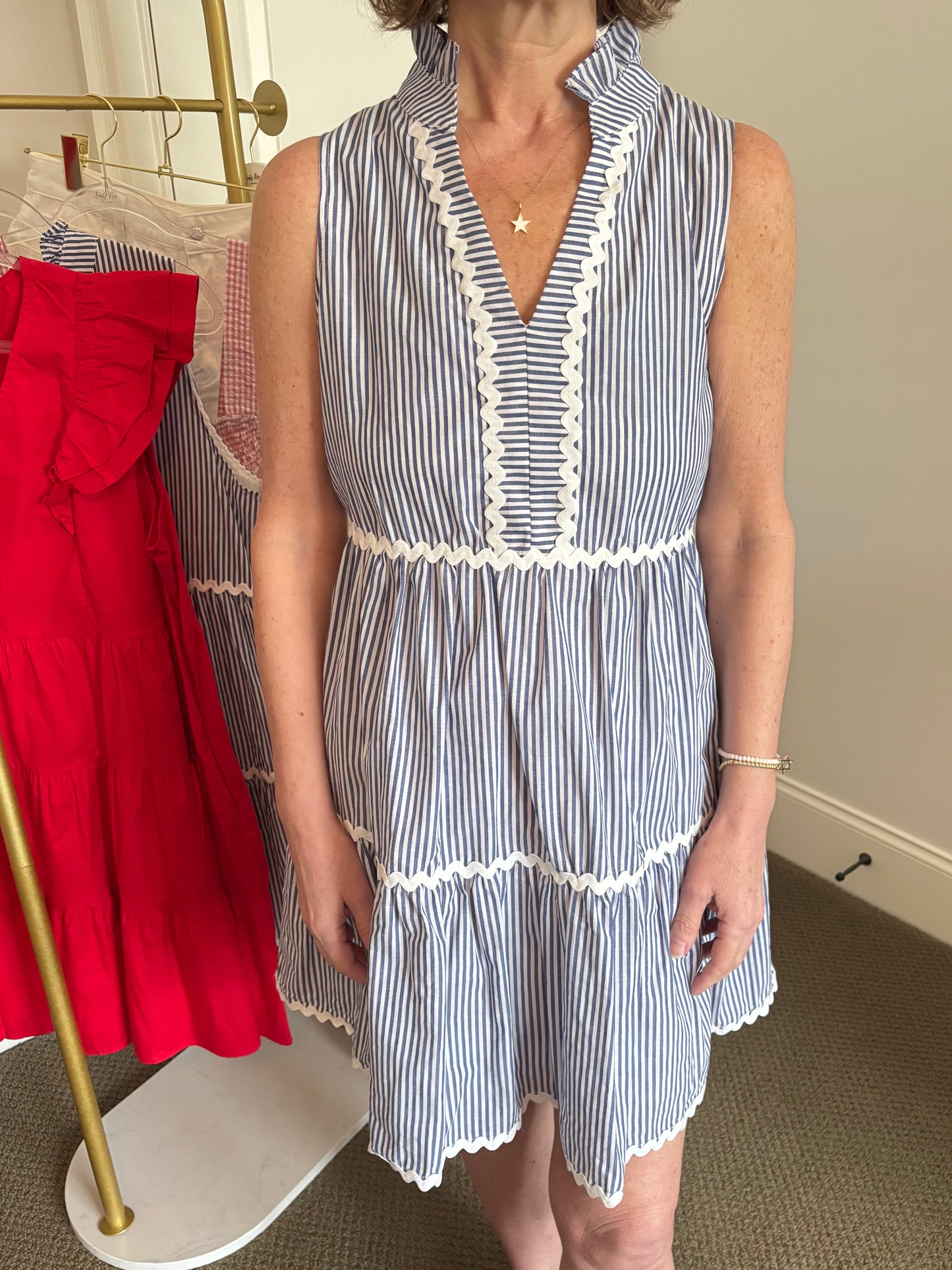 Woman wearing a blue and white striped dress with a red skirt in the background.