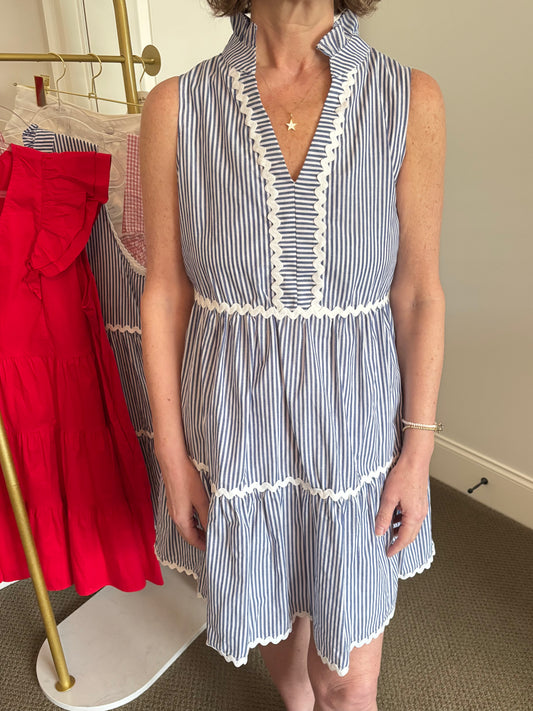Woman wearing a blue and white striped dress with a red skirt in the background.