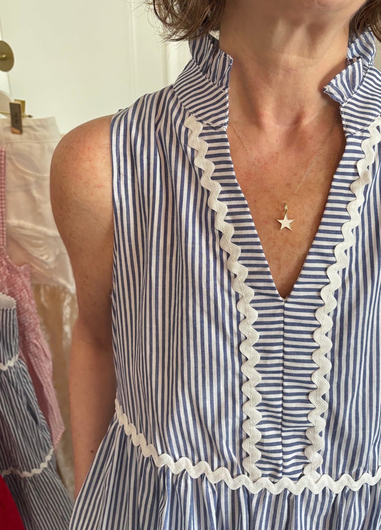 Woman wearing a blue and white striped dress with lace trim, standing against a neutral background.