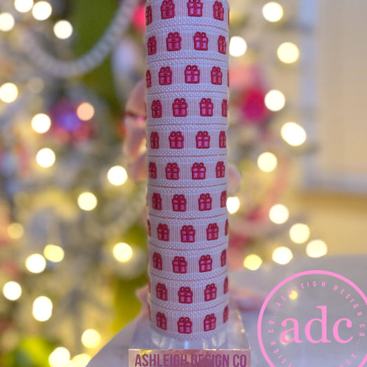 Stack of woven adjustable bracelets featuring red gift box pattern against a blurred Christmas tree background.